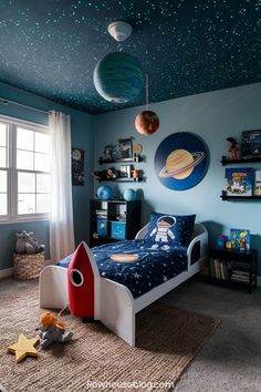 a child's bedroom decorated in blue and white with stars on the ceiling, space theme