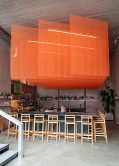 an empty room with chairs and tables in front of a large orange screen hanging from the ceiling