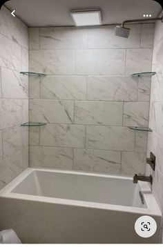 a white bath tub sitting inside of a bathroom next to a toilet and shower head