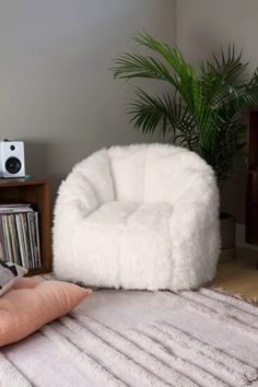 a white chair sitting on top of a wooden floor next to a rug and speakers