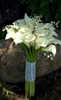 a bouquet of white flowers sitting on top of a rock