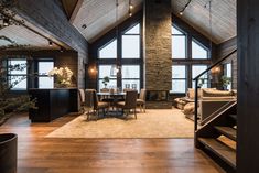 a living room filled with furniture next to tall windows and a staircase leading up to the second floor