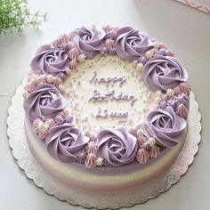 a birthday cake decorated with purple frosting roses