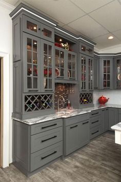 a kitchen with gray cabinets and marble counter tops