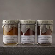 three jars filled with different types of food sitting on top of a stone counter next to each other