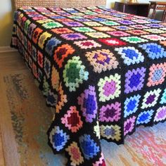 a multicolored crocheted bedspread on top of a bed in a room