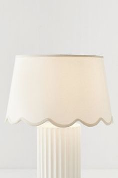 a table lamp with a white shade on it's base and a light bulb in the middle