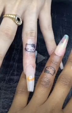 two people with hello kitty tattoos on their fingers