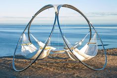 two hammocks are hanging in the sand by the water