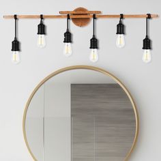 a bathroom with a round mirror and four light bulbs on the wall next to it