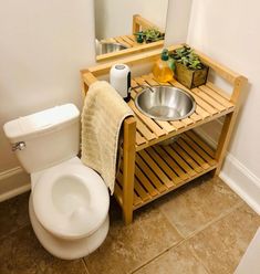 a bathroom with a sink, toilet and wooden rack for towels on the shelf next to it