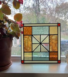 a potted plant sitting next to a window with a stained glass design on it