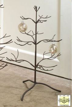 a metal christmas tree with three ornaments on it's branches and two balls hanging from the top