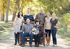 a family poses for a photo on a bench in the woods with trees behind them