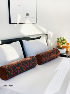 a bed with two pillows on it and an orange roll in front of the headboard