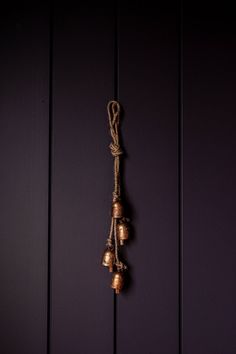 three bells hanging from a rope against a purple wall