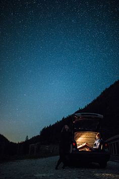 a man sitting in the back of a truck under a night sky filled with stars