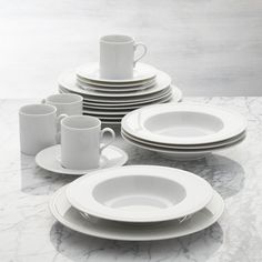 a table topped with white plates and cups next to each other on top of a marble counter