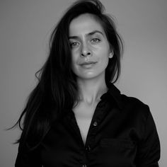 a black and white photo of a woman with long hair wearing a button up shirt