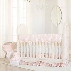 a white crib with pink ruffled bedding and a mirror on the wall