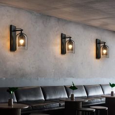 three lights are hanging on the wall above a couch in a room with tables and chairs