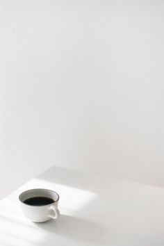 a cup of coffee sitting on top of a white table