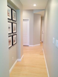 an empty hallway with pictures on the wall and wood flooring in front of it