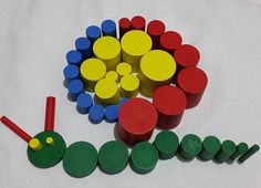 a group of wooden toys sitting on top of a white table covered in green, yellow and red shapes