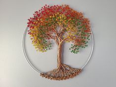 a metal wire tree with colorful beads on it's branches is displayed against a white wall