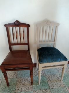 two wooden chairs sitting next to each other in a room with tile flooring and white walls