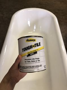 a hand holding a paint can in front of a white sink with the words tough - tile on it