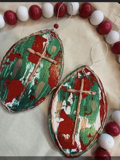 two red and green painted eggs are on a table next to white bead necklaces