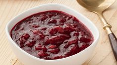 a white bowl filled with cranberry sauce next to a spoon