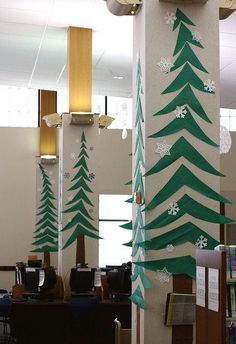 an office decorated for christmas with paper snowflakes and evergreen trees on the columns