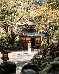 a woman standing in front of a building surrounded by trees