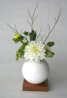 a white vase filled with flowers on top of a wooden stand