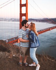 a man and woman kissing in front of the golden gate bridge