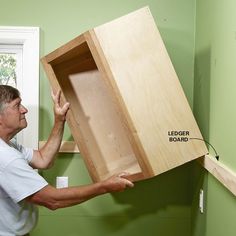 a man holding up a wooden box with the bottom section open and labeled below it