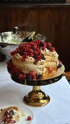 a cake with berries and cream on top sitting on a table next to other desserts