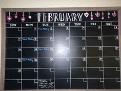 a chalk board with calendars on it and hearts drawn on the wall behind it