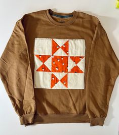 an orange and white patchwork design on a brown sweatshirt