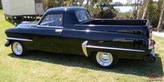 an old black pickup truck parked in the grass