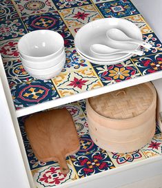 two bowls and wooden spoons are on the shelf in this colorful tiled kitchen area