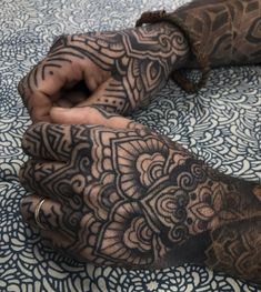 a person's hands with tattoos on them and one hand holding the other arm