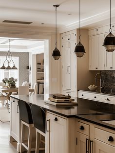 a large kitchen with white cabinets and black counter tops, along with bar stools