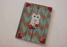 a notebook with an owl on it sitting on top of a wooden table next to a wall