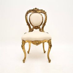 an ornate gold chair with white upholstered seat and back cushion, against a white background