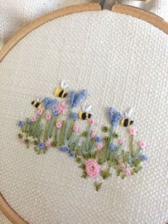 a close up of a embroidery on a piece of cloth with flowers and bees in it