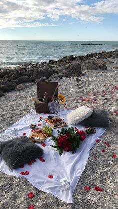 a picnic set up on the beach with food and flowers