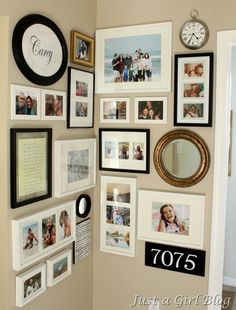 a wall filled with pictures and framed photos next to a clock on the side of a wall